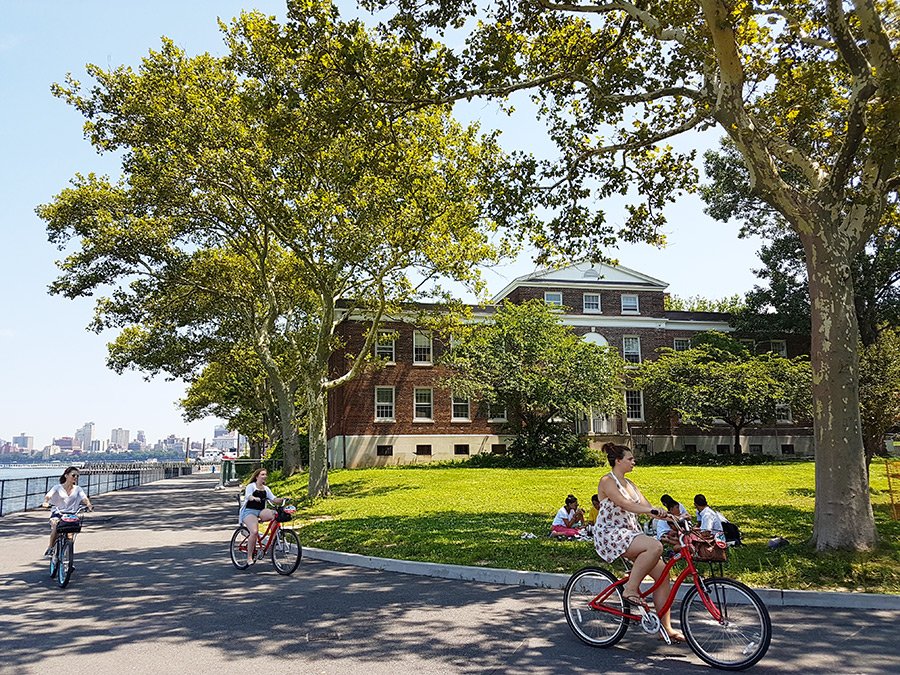 Ciclistas recorriendo la Isla de los Gobernadores al sur de Manhattan, al fondo edificaciones históricas - Foto de Andrea Hoare Madrid
